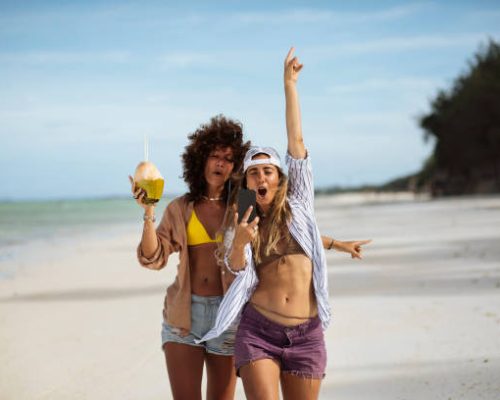 Two young women recording themselves while enjoying a summer day at the beach