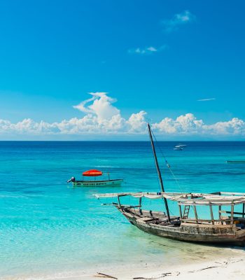 Wooden fishing ship on the white sand beach on low tide, Indian ocean. Zanzibar, Tanzania.